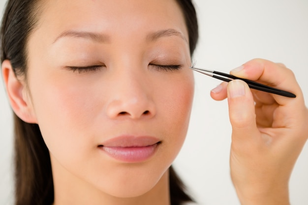 Femme plaçant faux cils sur un patient