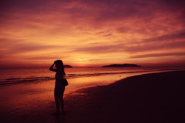 Femme sur la plage au coucher du soleil