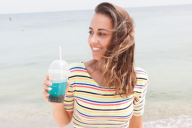 Femme de plage buvant une boisson froide et s'amusant à la fête sur la plage