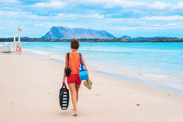 Femme sur la plage de La Cinta et l'île de Tavolara, San Teodoro, Sardaigne, Italie