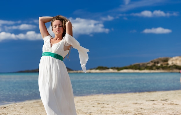 Photo femme sur la plage ensoleillée de la mer en robe blanche flottant elafonissi grece