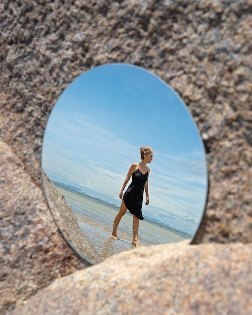 Femme à la plage en été posant avec miroir rond