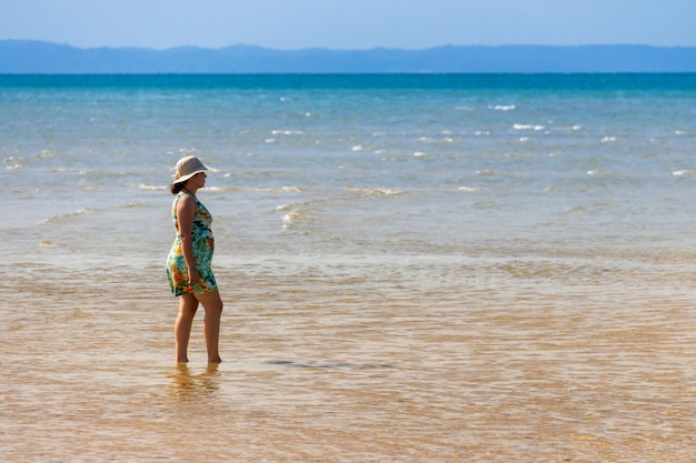 Femme sur la plage à l'intérieur de la mer regardant l'horizon