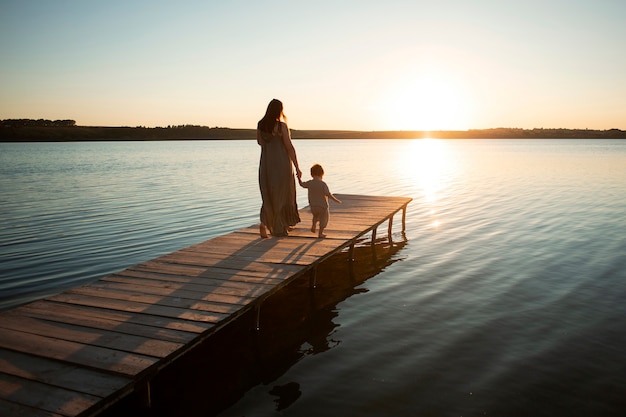 Femme à la plage avec son bébé profitant du coucher de soleil