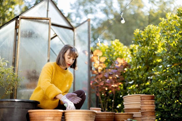 Femme plantant des fleurs dans des cruches au jardin