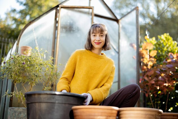 Femme plantant des fleurs dans des cruches au jardin