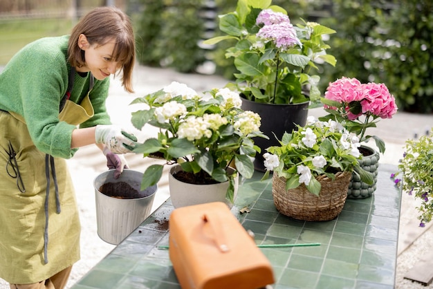 Femme plantant des fleurs dans des pots sur la table dans le jardin