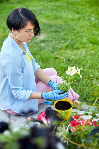 Femme plantant des fleurs de pétunia surfinia concept de jardinage en pot à la maison