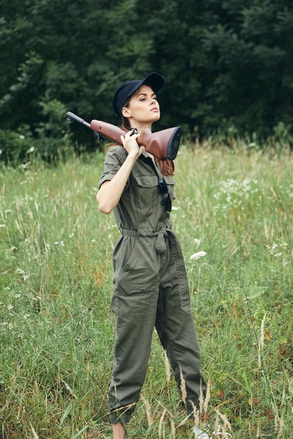 Femme en plein air avec une arme à feu sur son épaule combinaison verte voyage style de vie armes