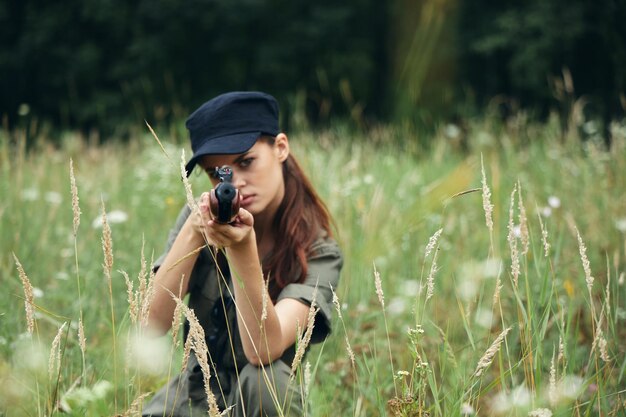 Une femme en plein air assise sur l'herbe vise avec un abri d'armes d'armes