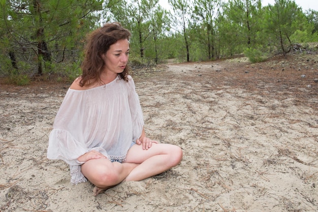 Femme en plein air en été s'asseoir sur le parc de la forêt de pins nature sablonneuse