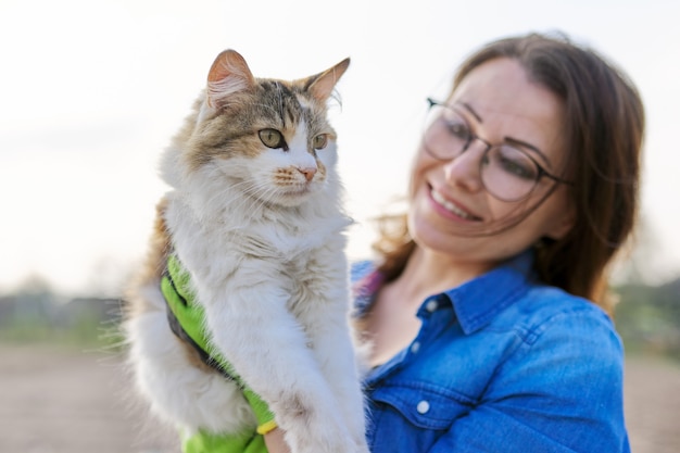 Femme en plein air tenant un chat domestique dans les bras et lui parlant, amitié du propriétaire et de l'animal de compagnie