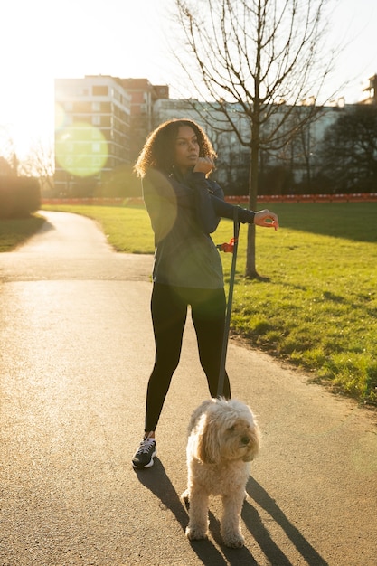 Femme plein coup avec un chien mignon à l'extérieur