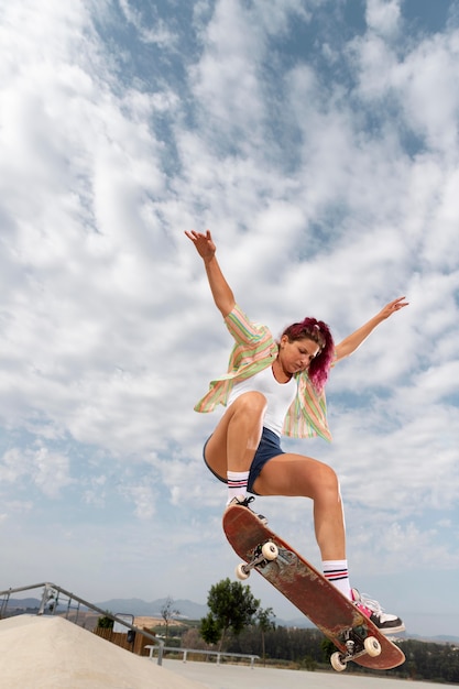 Photo femme de plein coup sautant avec une planche à roulettes