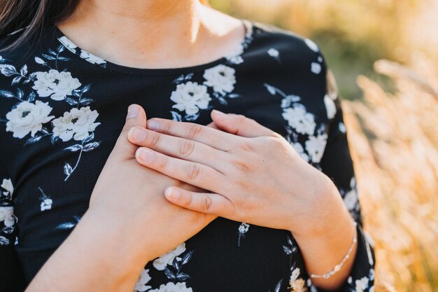 Femme pleine d'espoir mettant les mains sur son cœur en signe de gratitude pour les bénédictions de Dieu, sur le terrain. Copier l'espace