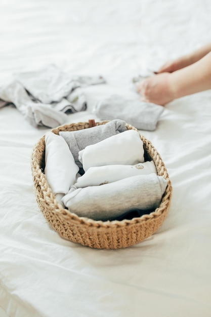 Photo femme pliant des vêtements dans un panier de jute dans le système konmari concept d'organisation de vêtements minimalistes