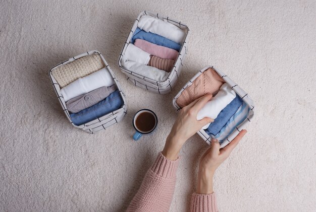 La femme plie soigneusement les vêtements et les met dans des paniers et des boîtes. Minimalisme dans le style scandinave.