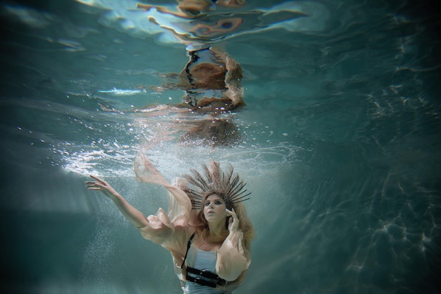 Une femme plonge sous l'eau parmi les rayons de lumière et les bulles d'air.