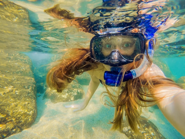Femme plongée en apnée dans les eaux tropicales devant une île exotique