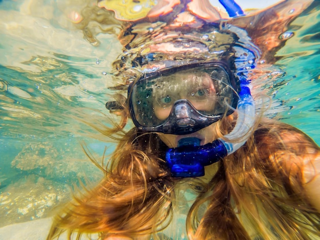 Femme plongée en apnée dans les eaux tropicales devant une île exotique