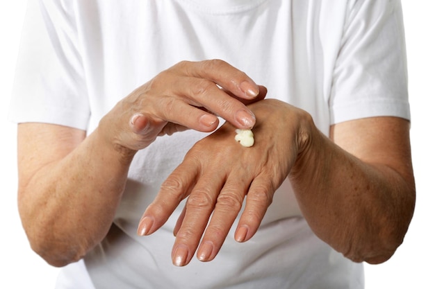 Femme plus âgée appliquant de la crème sur les mains en gros plan