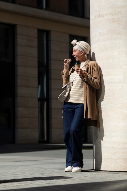 Femme plus âgée à l'extérieur de la ville parlant au téléphone tout en prenant un café