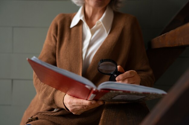 Photo femme plus âgée lisant tout en utilisant une loupe