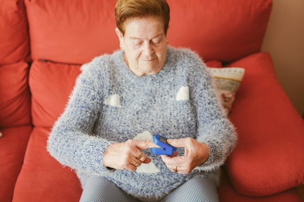 Une femme plus âgée met un oxymètre à son doigt pour passer un test Covid