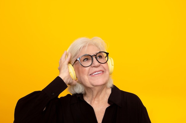 Femme plus âgée souriante avec un casque écoutant de la musique