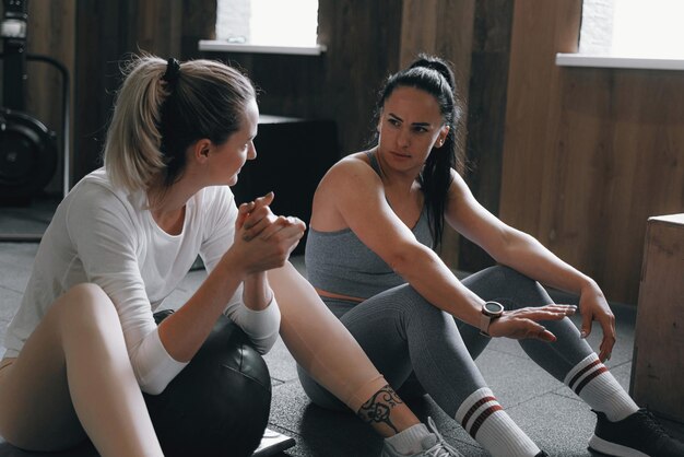 Une femme de plus de trente ans dans la salle de sport effectue des exercices sous la direction d'un entraîneur expérimenté