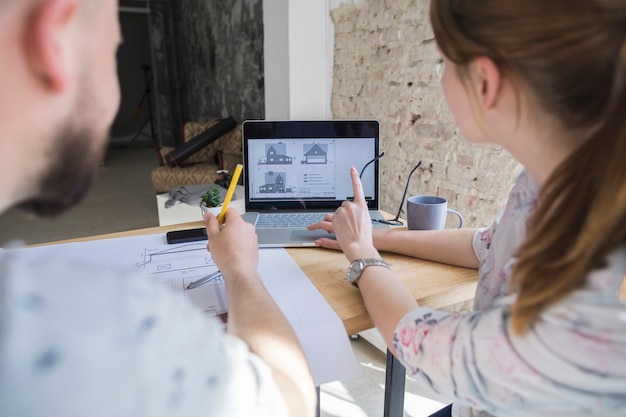 Femme pointant sur l&#39;écran d&#39;un ordinateur portable tout en travaillant avec son collègue au lieu de travail