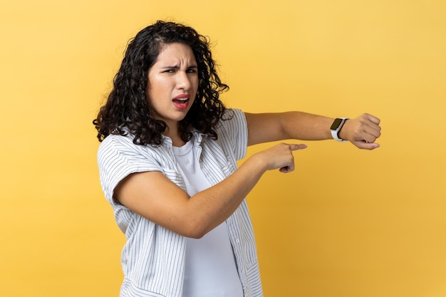 Femme pointant la montre-bracelet et regardant ennuyé mécontent montrant l'horloge pour se dépêcher