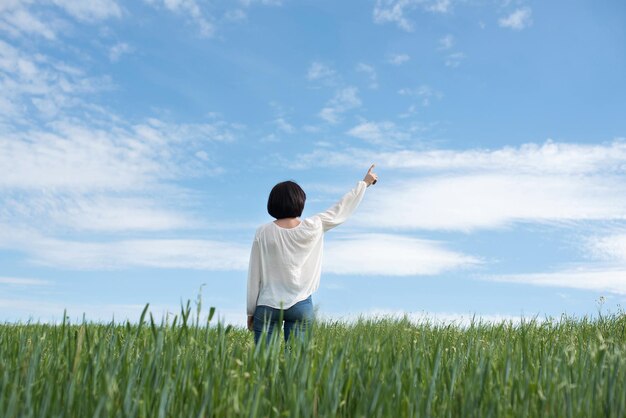 Femme pointant vers le fond dans un champ vert