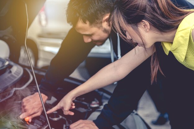 Photo une femme pointe sur le moteur pendant qu'un homme répare une voiture.