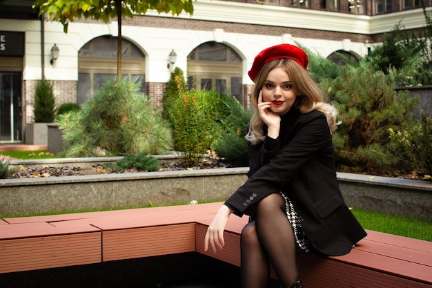 Une femme portant un béret rouge est assise sur un banc