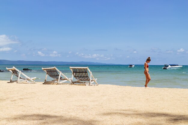 Femme portant le bikini et marchant sur la plage du côté droit