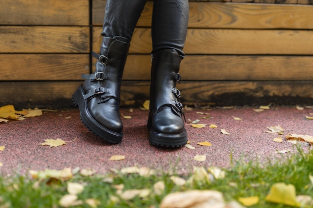 Une femme portant des bottes noires est assise sur un banc en bois.