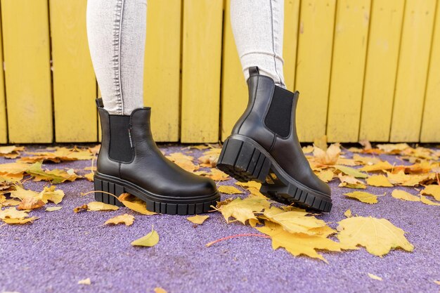 Photo femme portant des bottes noires avec une semelle en caoutchouc noir debout sur un fond violet.