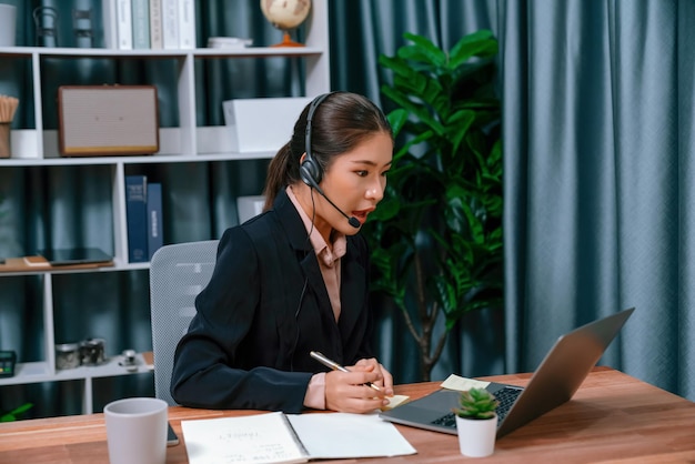 Une femme portant un casque est assise à un bureau devant un ordinateur portable.