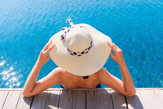 Femme portant un chapeau alors qu'elle est assise dans la piscine