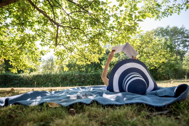 Photo une femme portant un chapeau de paille dans la nature d'été lisant un livre