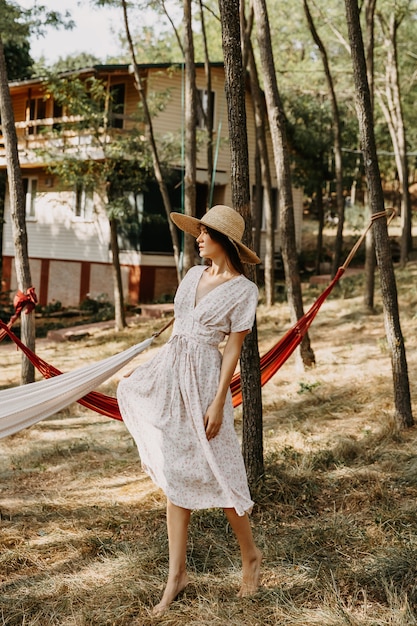 Femme portant un chapeau de paille et une robe d'été dans une forêt