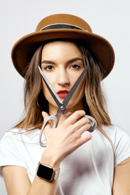 Une femme portant un chapeau regardant à travers des ciseaux de haute qualité