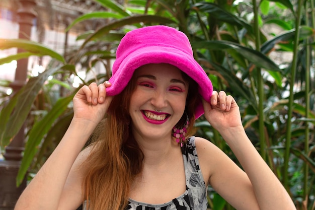 Une femme portant un chapeau rose sourit à la caméra.