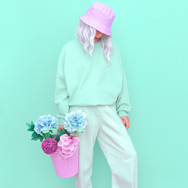 Photo femme portant un chapeau tenant des fleurs debout contre un fond coloré