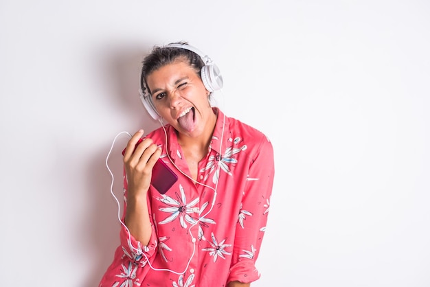 Une femme portant une chemise hawaïenne chante et porte des écouteurs et porte une chemise hawaïenne rose.