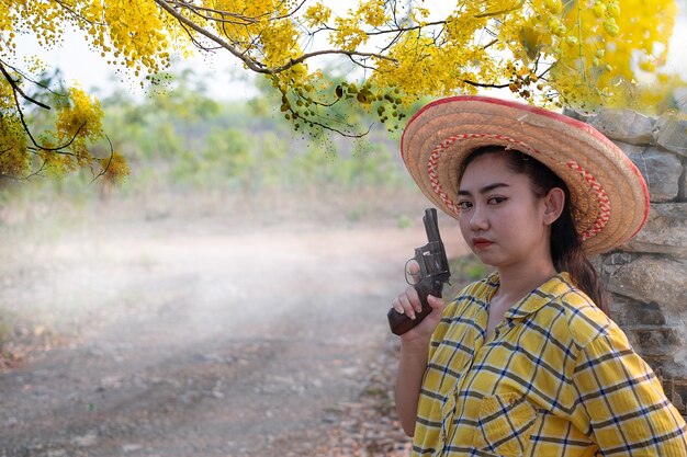 Femme portant une chemise jaune hand holding old revolver gun dans la ferme Jeune fille avec