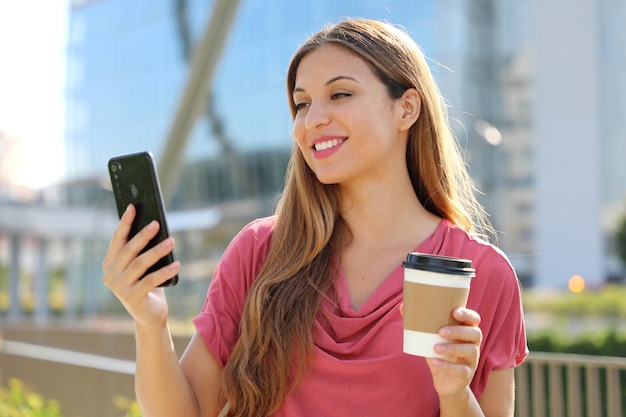 Femme portant un chemisier rose appel vidéo avec smartphone à l'extérieur