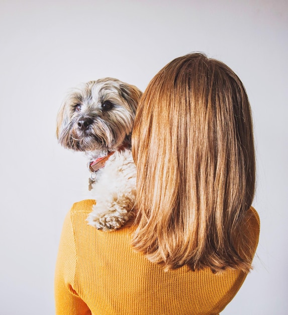 Femme portant un chien alors qu'elle se tient contre le mur