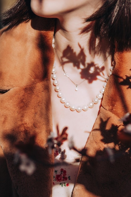Une femme portant un collier de perles avec des ombres de fleurs printanières dessus